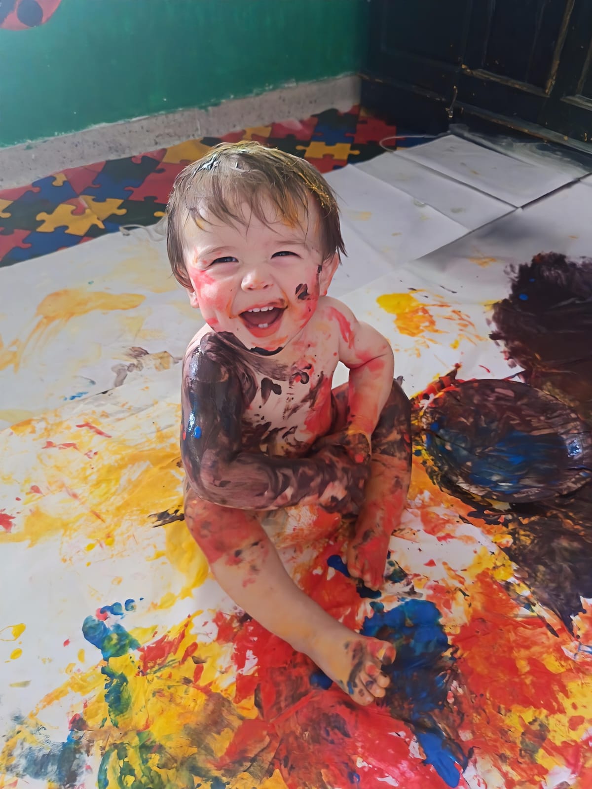 Niño feliz cubierto de pintura durante actividad artística libre